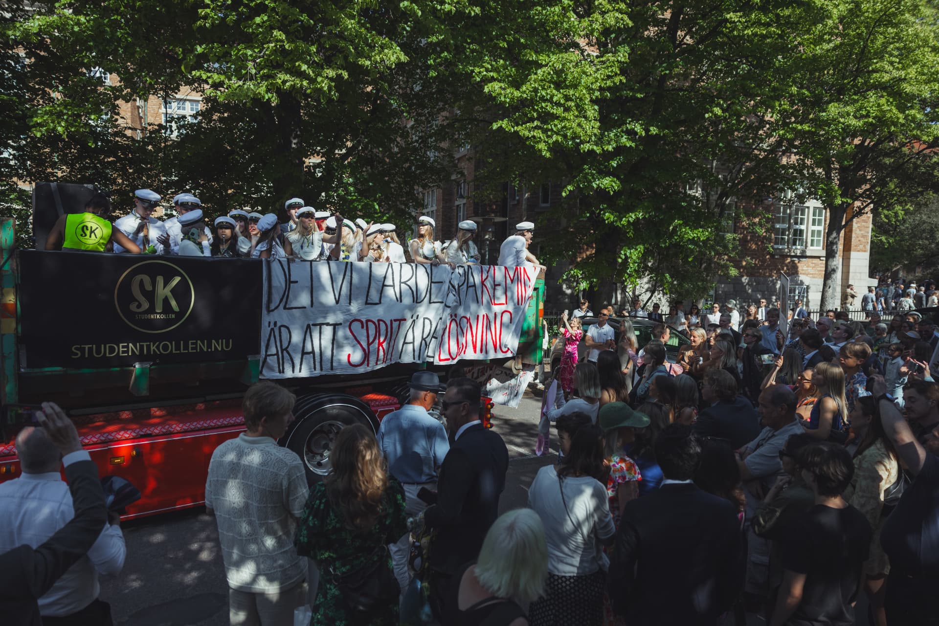 Studentflak med banderoll kör förbi jublande publik